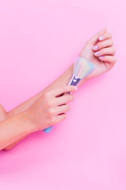 Pembe arka plan üzerinde pembe manikür ile elinde pembe fırça.
