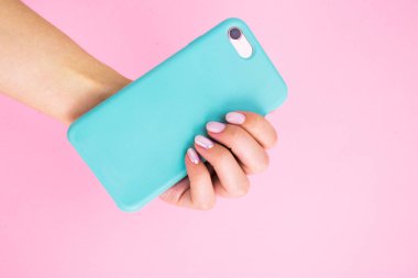 Pembe arka plan üzerinde manikür ile elinde nane durumda Akıllı telefon.
