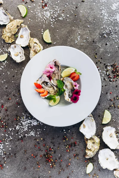 Gri bir arka plan üzerinde çiçeklerle süslenmiş bir çanak üzerinde Istiridye. Aphrodisiacs. 