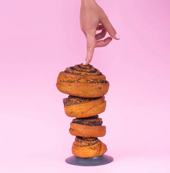 手はピンクの背景にパンを指します。ベーキング広告. — ストック写真