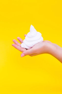 Sarı bir arka plan üzerinde bir el üzerinde tıraş köpüğü.