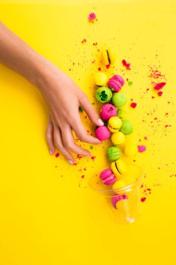 Sarı bir arka plan üzerinde renkli, parlak, tatlı macaroons. Yer çekimine karşı. Asimetri.