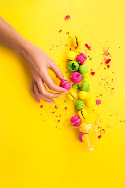 Sarı bir arka plan üzerinde renkli, parlak, tatlı macaroons. Yer çekimine karşı. Asimetri.
