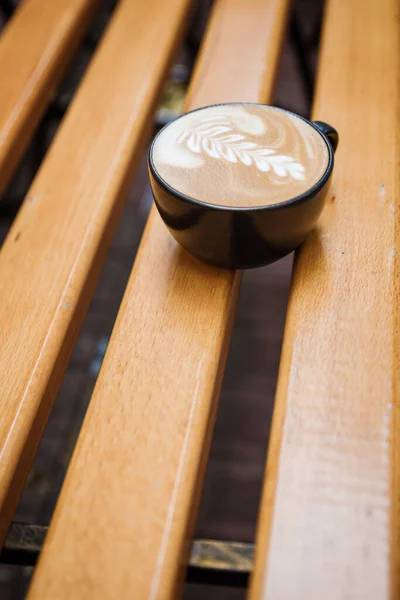 Ceașcă de cappuccino cu un model pe o bancă de lemn . — Fotografie, imagine de stoc