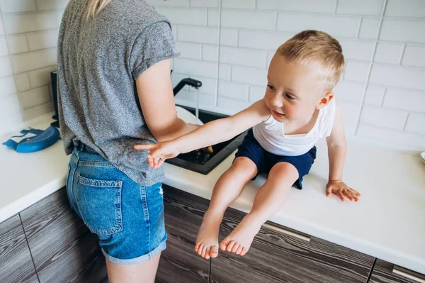 Menino que está de pé na cozinha com a mãe. — Fotografia de Stock