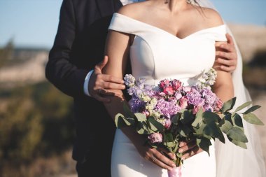 Düğün asimetrik mor buketi gelinin ellerinde.