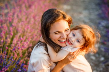 Anne, gün batımında lavanta tarlasında kızını kucaklıyor..