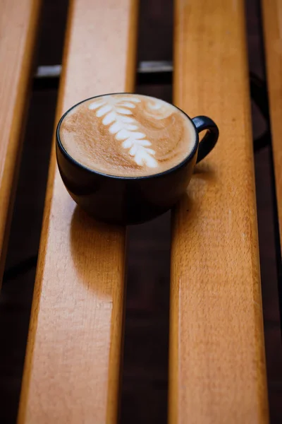 Šálek cappuccino se vzorem na dřevěné lavičce. — Stock fotografie