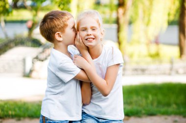 Çocuk kızların kulağına bir sır fısıldıyor. Çocuklar parkta yürüyüşe çıktı..