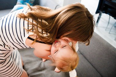 Anne ve kızı evlerinde kucaklaşıyorlar. Mutlu bir aile. Çocuk yetiştiren bir anne..