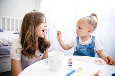 Anne ve kızı birlikte resim yapıyorlar. Çocuk annesiyle resim çiziyor..