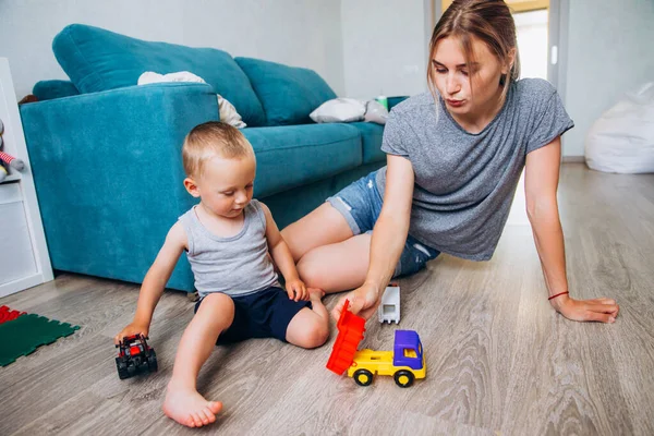 Mamma leker med sin son i ett rum med leksaksbilar. — Stockfoto