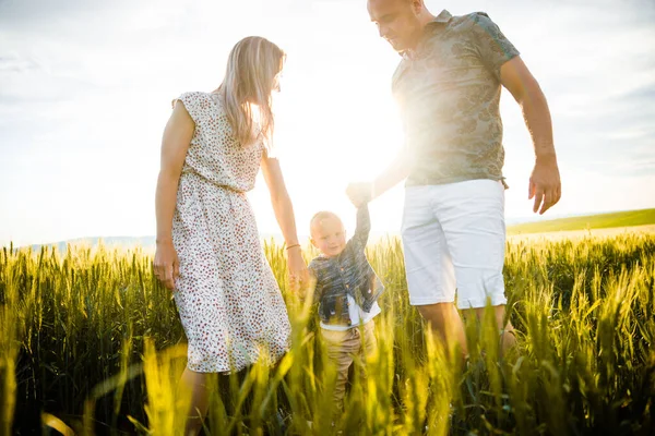 Família feliz na grama verde brilhante ao pôr do sol. — Fotografia de Stock