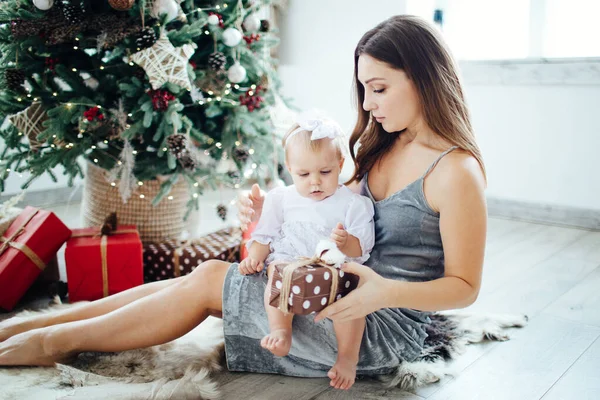 Matka a dcera otevřít Nový rok dárky pod vánoční stromeček. — Stock fotografie