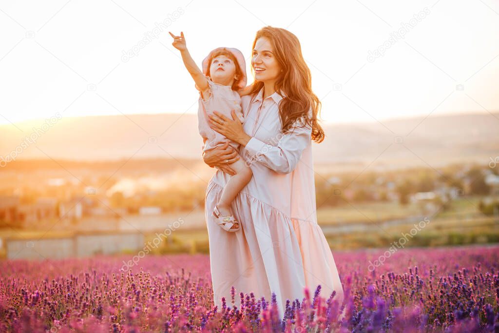 Happy family in a field at sunset. The kid smiles at his mother