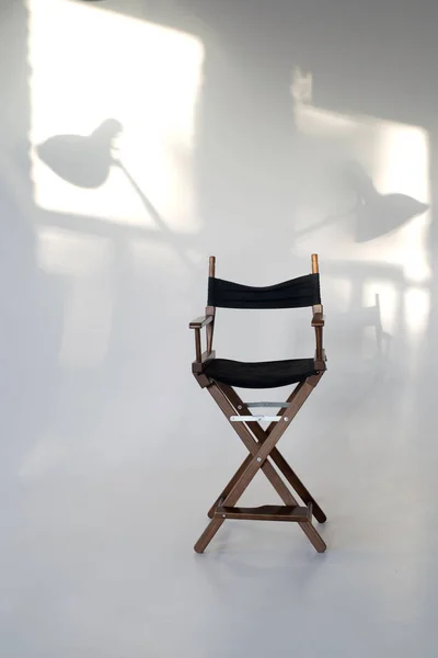 director\'s chair on a white background. shadows on the wall from the sun. light shades