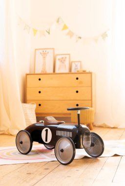Çocuk odasında Retro tarzı çocuk yarış arabası. Oğlan için siyah klasik yarış arabası modeli. Çocukların yatak odası. Bebekler için araç gereç. İskandinav tarzı. yakın plan