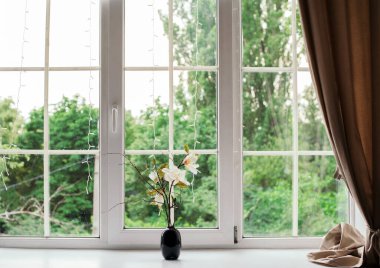 Odadaki pencere eşiğinde güzel, yalnız bir çiçek vazosu, mesaj için yer. Perdeler ve büyük bir pencere. yeşil arkaplan.