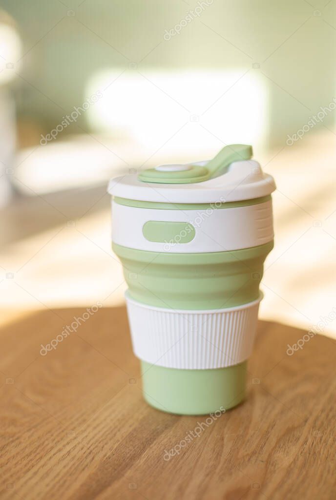 Foldable silicone cup for drinks without plastic in the style of zero waste on a interior background, close-up. Product photography. Store content.