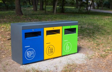 Parkta atık ayıklamak için üç farklı çöp konteynırı. Plastik için sarı, cam için yeşil, kağıt için mavi. Çöplerin ayrıştırılması ve sıralanması, çevre kirliliği kavramı