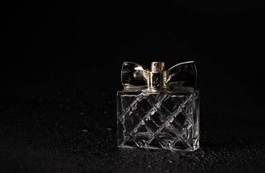 Siyah arka planda su damlaları olan bir şişe kadın parfümü. güzellik ve tarz kavramı.