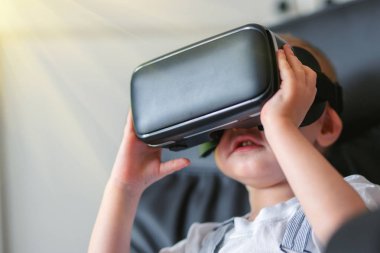 Çocuk yeni Sanal Gerçeklik, Vr karton gözlük kullanarak. kanepede oturan sanal gerçeklik kulaklık ile mutlu küçük çocuk. Tonlu fotoğraf