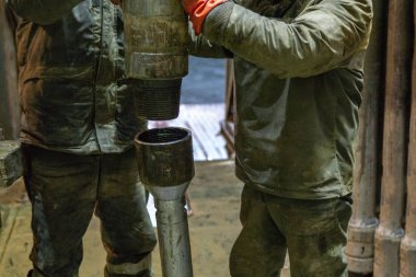 Offshore petrol kuyusu işçisi kuyu başındaki petrol kuyusunda delik açmak için alet ve ekipman hazırlayın. Sondaj borusu bağlantısı kuruyorum. Tribünlerin arasından matkap borusu bağlantısı için bir görünüm.