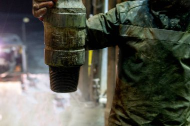 Offshore petrol kuyusu işçisi kuyu başındaki petrol kuyusunda delik açmak için alet ve ekipman hazırlayın. Sondaj borusu bağlantısı kuruyorum. Tribünlerin arasından matkap borusu bağlantısı için bir görünüm.