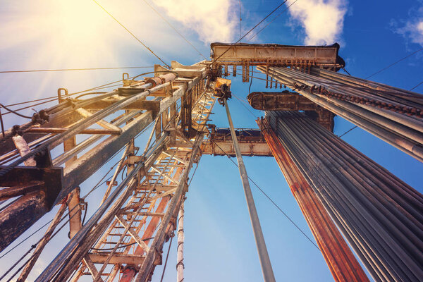 Наземная вышка в нефтегазовой отрасли. Буровая установка против голубого неба с облаками
