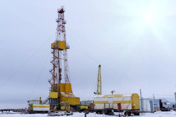 Silhouette image of oil and gas drilling rig in the middle of nowhere with dramatic sky. Onshore land rig in oil and gas industry. Land oil drilling rig blue sky.