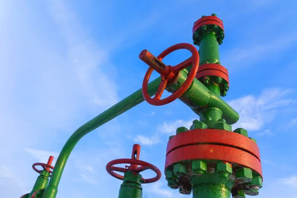 Horizontal view of a wellhead with valve armature. Oil and gas industry concept.  Oil valve with rocking in the background. Offshore oil and gas site service operator open valve for control gases.