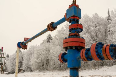 Kapak armatürü olan bir kuyu başının yatay görünümü. Petrol ve gaz endüstrisi kavramı. Arka planda sallanan yağ vanası. Kontrol gazları için offshore petrol ve gaz saha servisi operatörü açık vana.