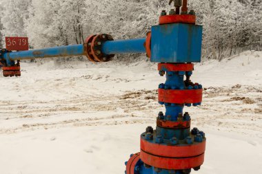 Kapak armatürü olan bir kuyu başının yatay görünümü. Petrol ve gaz endüstrisi kavramı. Arka planda sallanan yağ vanası. Kontrol gazları için offshore petrol ve gaz saha servisi operatörü açık vana.