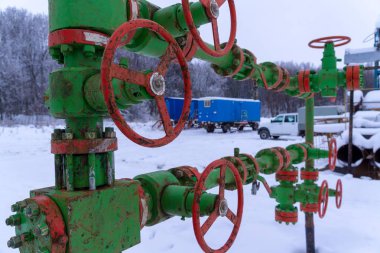 Kapak armatürü olan bir kuyu başının yatay görünümü. Petrol ve gaz endüstrisi kavramı. Arka planda sallanan yağ vanası. Kontrol gazları için offshore petrol ve gaz saha servisi operatörü açık vana.