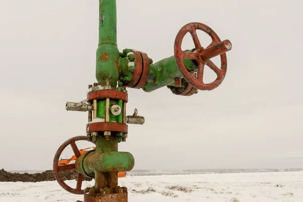 Horizontal view of a wellhead with valve armature. Oil and gas industry concept.  Oil valve with rocking in the background. Offshore oil and gas site service operator open valve for control gases.