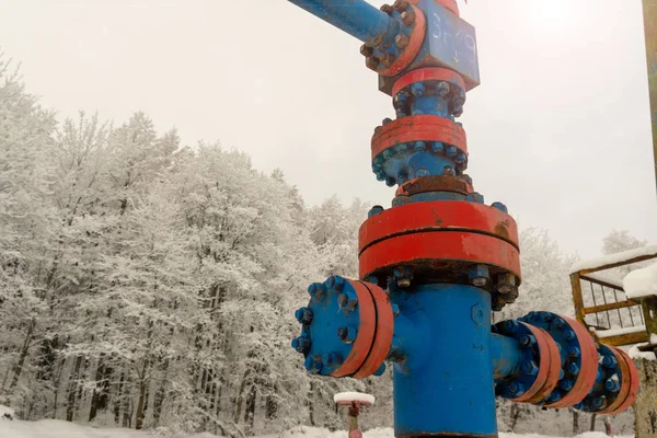 Horizontal view of a wellhead with valve armature. Oil and gas industry concept.  Oil valve with rocking in the background. Offshore oil and gas site service operator open valve for control gases.