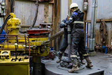 Offshore petrol kuyusu işçisi kuyu başındaki petrol kuyusunda delik açmak için alet ve ekipman hazırlayın. Sondaj borusu bağlantısı kuruyorum. Tribünlerin arasından matkap borusu bağlantısı için bir görünüm.
