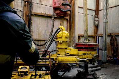 Offshore petrol kuyusu işçisi kuyu başındaki petrol kuyusunda delik açmak için alet ve ekipman hazırlayın. Sondaj borusu bağlantısı kuruyorum. Tribünlerin arasından matkap borusu bağlantısı için bir görünüm.