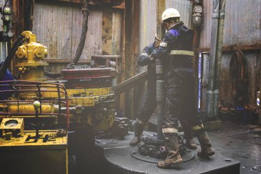 Offshore petrol kuyusu işçisi kuyu başındaki petrol kuyusunda delik açmak için alet ve ekipman hazırlayın. Sondaj borusu bağlantısı kuruyorum. Tribünlerin arasından matkap borusu bağlantısı için bir görünüm.