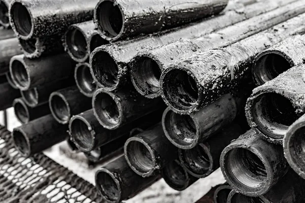 Oil Drill pipe. Rusty drill pipes were drilled in the well section.   View of the shell of drill pipes laid in courtyard of the oil and gas warehouse. Black and white photo