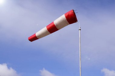 Rüzgarlı havalarda açık mavi gökyüzü arka plan havaalanı windsock da denilen yerel rüzgar yönü gösterir: hava çorap, drogue, rüzgar kol, rüzgar konisi . Mavi gökyüzüne karşı kırmızı beyaz çizgili windsock 