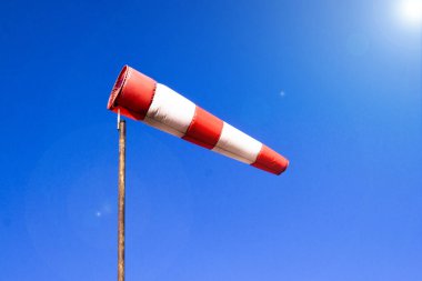 Rüzgarlı havalarda açık mavi gökyüzü arka plan havaalanı windsock da denilen yerel rüzgar yönü gösterir: hava çorap, drogue, rüzgar kol, rüzgar konisi . Mavi gökyüzüne karşı kırmızı beyaz çizgili windsock 