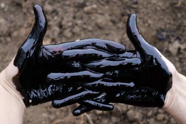 yağ sızıntısı. Çok kirli bir el. Leke elleri toprak arka planda siyah yağ ile başparmak gösteren. el Ok gösteren.