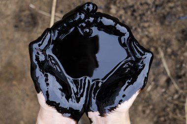 Yağ sızıntısı. Çok kirli bir el. Toprak zemininde siyah yağ olan elleri gösteriyor..