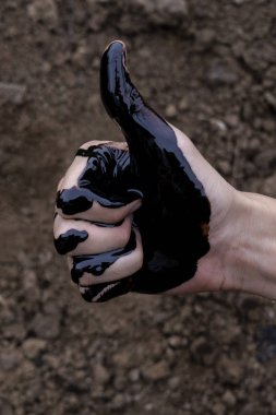 yağ sızıntısı. Çok kirli bir el. Leke elleri toprak arka planda siyah yağ ile başparmak gösteren. el Ok gösteren