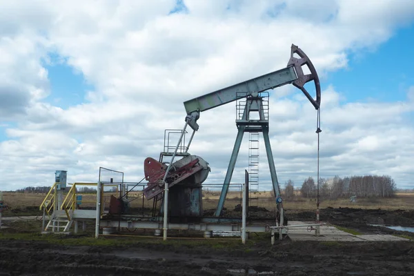 L'unità di pompaggio del fascio è compiti a casa, tramonto nel campo petrolifero. Pompa olio olio impianto di perforazione energia macchina industriale per il petrolio. L'unità di pompaggio come la pompa installata su un pozzo. Attrezzature dei giacimenti petroliferi — Foto Stock