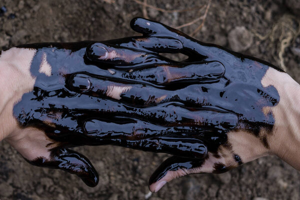 oil leaking. Very dirty hand.Stain hands showing thumbs up with black oil on soil background.