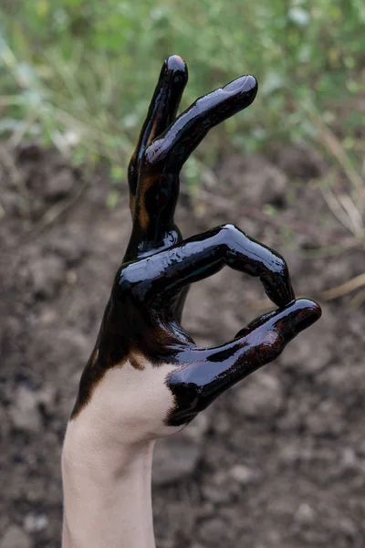 oil leaking. Very dirty hand.Stain hands showing thumbs up with black oil on soil background. hand showing OK