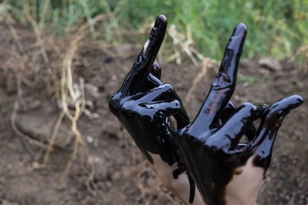 oil leaking. Very dirty hand.Stain hands showing thumbs up with black oil on soil background.