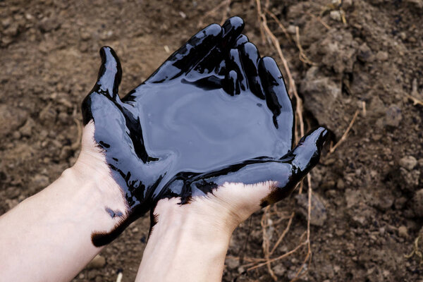 oil leaking. Very dirty hand.Stain hands showing thumbs up with black oil on soil background.
